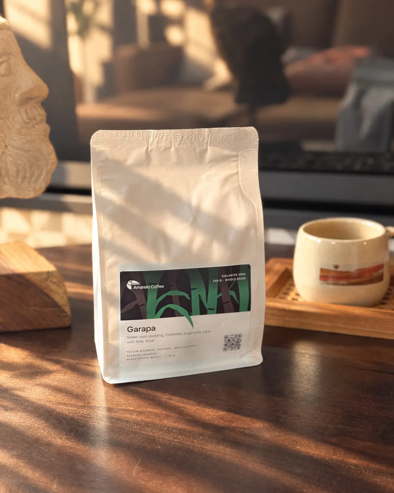 A Garapa bag on a wooden table, next to a mug of coffee