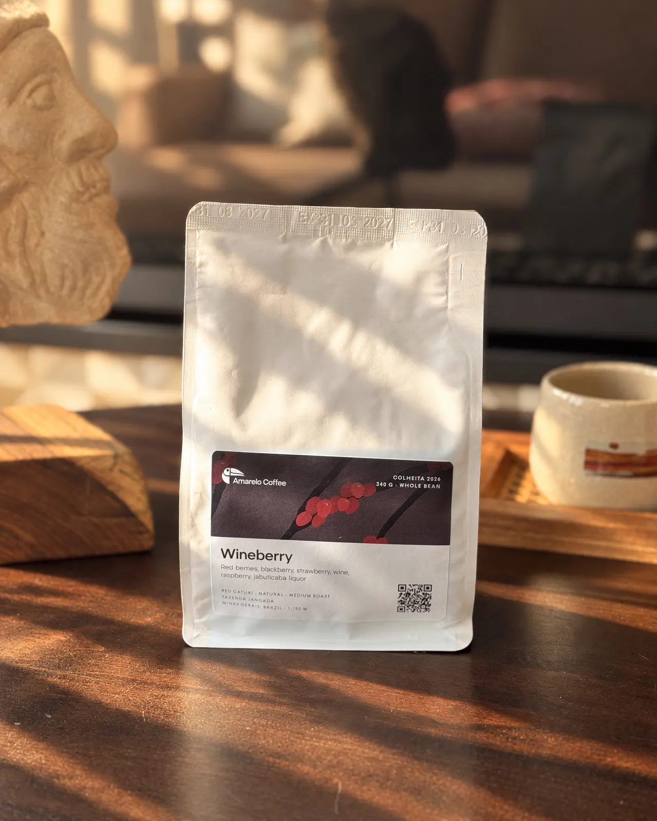 A Wineberry bag on a wooden table, next to a mug of coffee